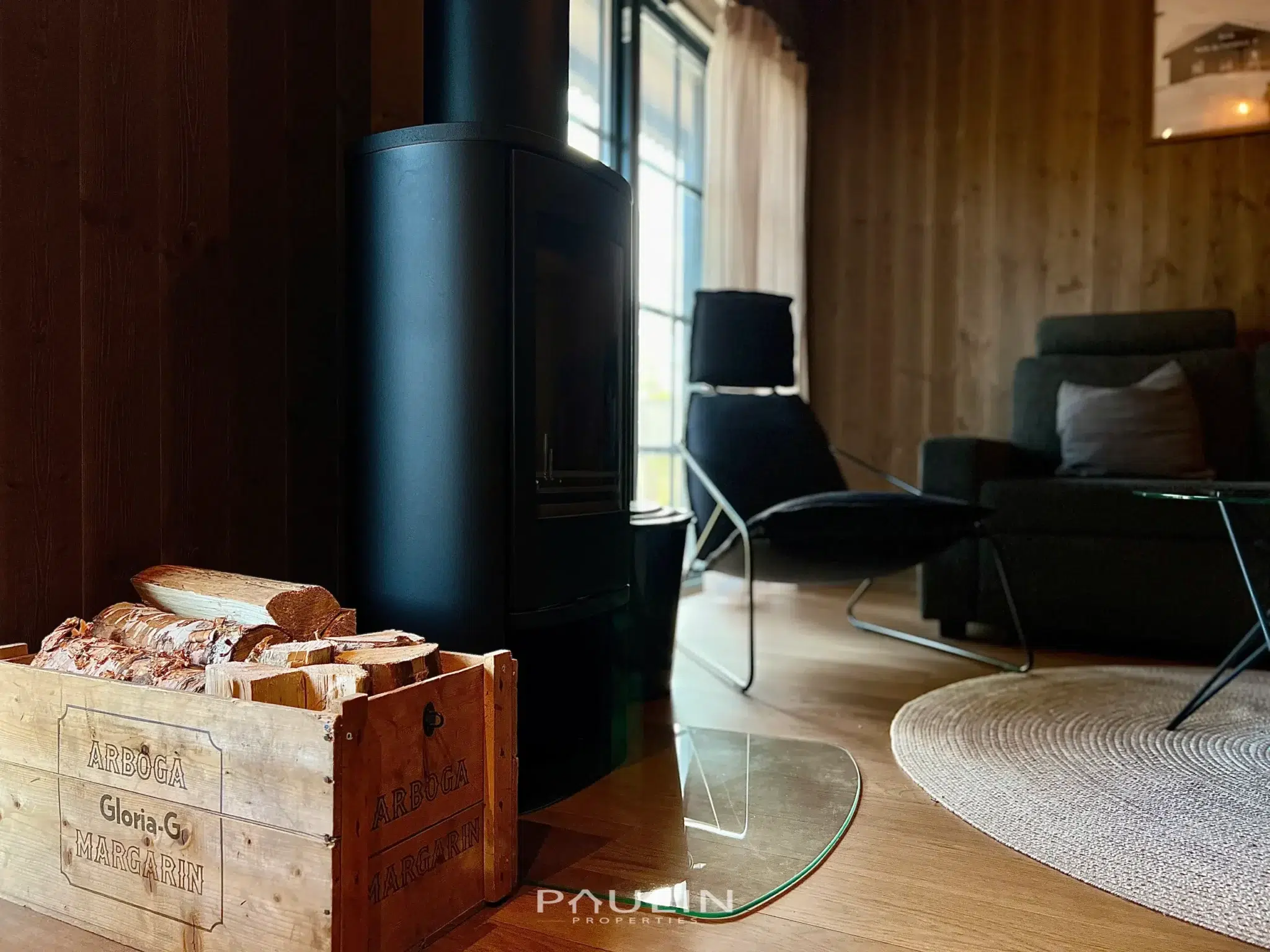 Mysigt vardagsrum i Fjällbäcken 9B med braskamin och trälåda med ved – rustik fjällkänsla i Sälen